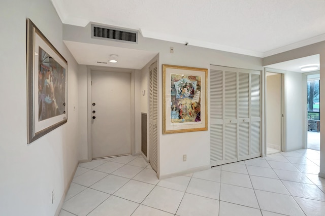 corridor with light tile patterned flooring and crown molding