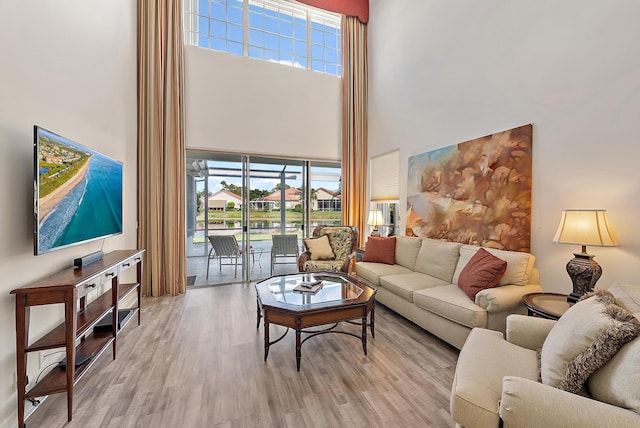 living room featuring light wood-type flooring and a towering ceiling