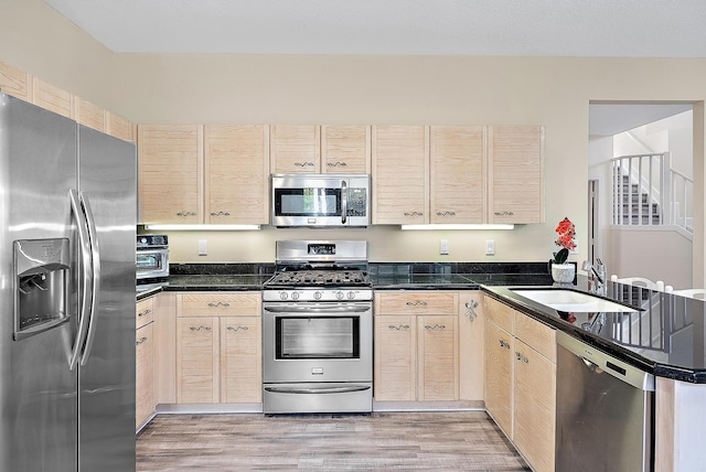 kitchen with sink, kitchen peninsula, light hardwood / wood-style flooring, stainless steel appliances, and light brown cabinetry