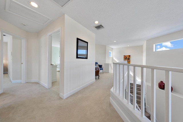 hallway with light carpet and a textured ceiling