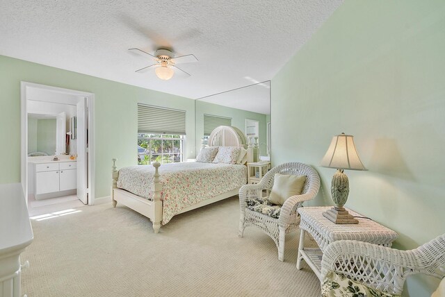 carpeted bedroom featuring connected bathroom, ceiling fan, and a textured ceiling