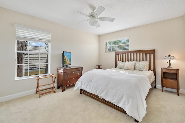 carpeted bedroom featuring ceiling fan and a textured ceiling