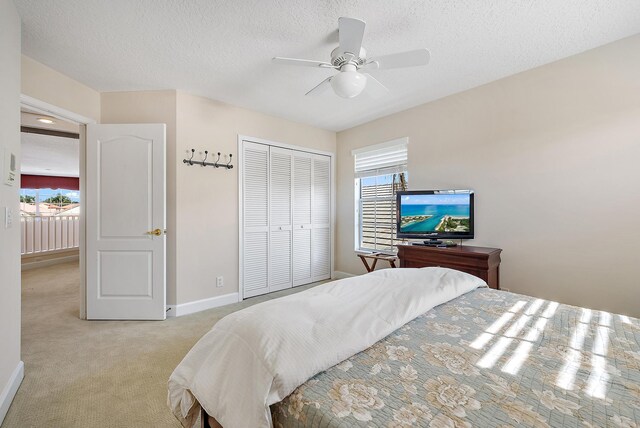 carpeted bedroom featuring a textured ceiling, ceiling fan, and a closet