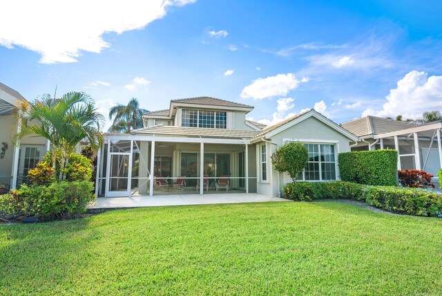 rear view of house with a sunroom, a lawn, and a patio