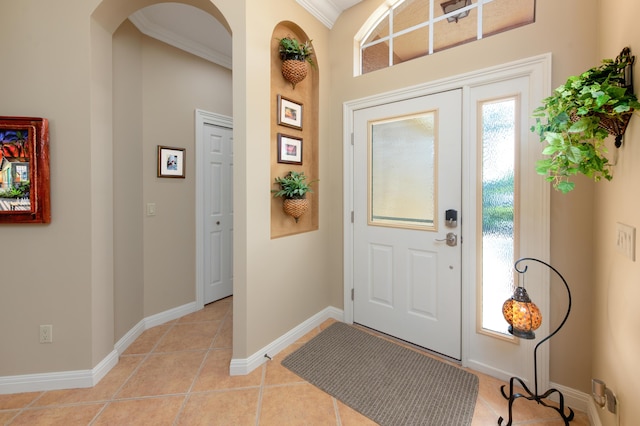 entrance foyer featuring arched walkways, crown molding, baseboards, and light tile patterned floors