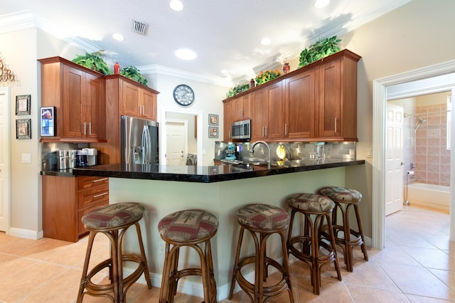 kitchen featuring light tile patterned floors, visible vents, dark countertops, brown cabinets, and stainless steel appliances