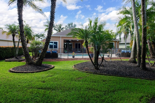 rear view of house featuring a lawn, fence, a fenced in pool, and stucco siding