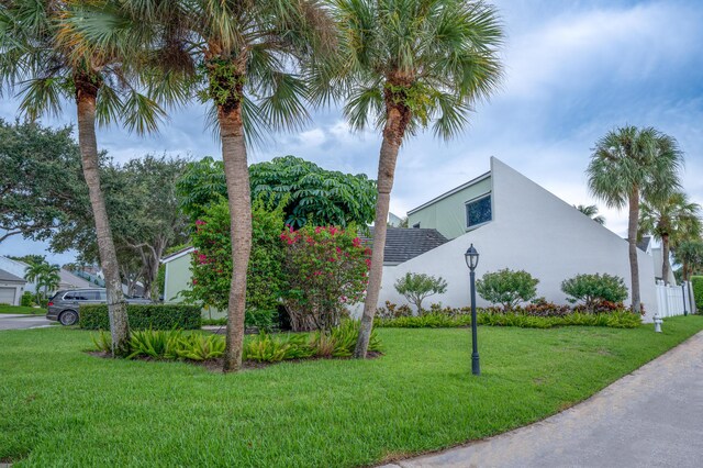 view of side of home with stucco siding, a lawn, and fence