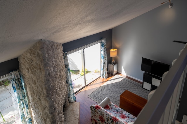 living room featuring a wealth of natural light, vaulted ceiling, hardwood / wood-style floors, and a textured ceiling