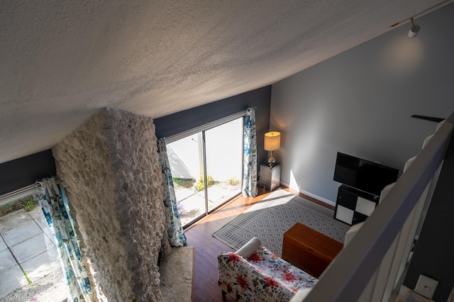 living room with a textured ceiling, hardwood / wood-style floors, and lofted ceiling