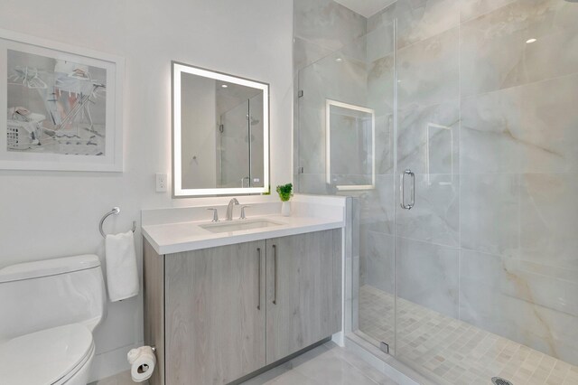 bathroom featuring vanity, toilet, and a shower with door