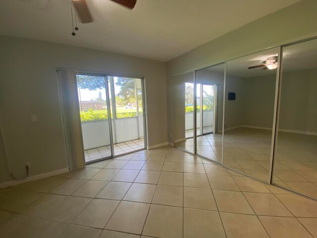 unfurnished bedroom featuring access to outside, light tile patterned floors, and ceiling fan