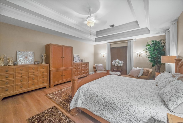 bedroom featuring ceiling fan, a tray ceiling, light hardwood / wood-style flooring, and crown molding