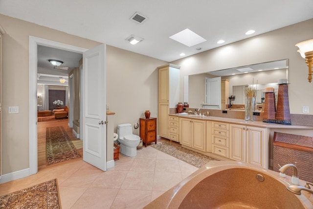 bathroom with a bathing tub, toilet, a skylight, vanity, and tile patterned floors