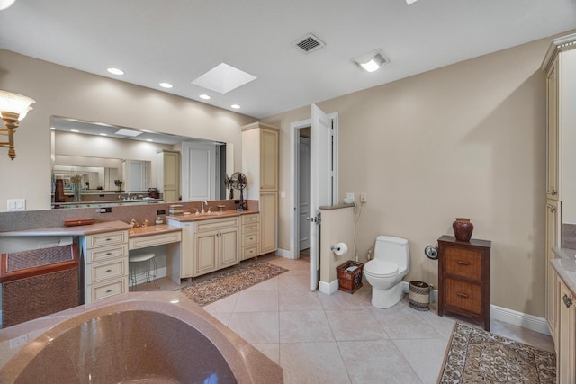 bathroom with toilet, vanity, tile patterned floors, and a skylight