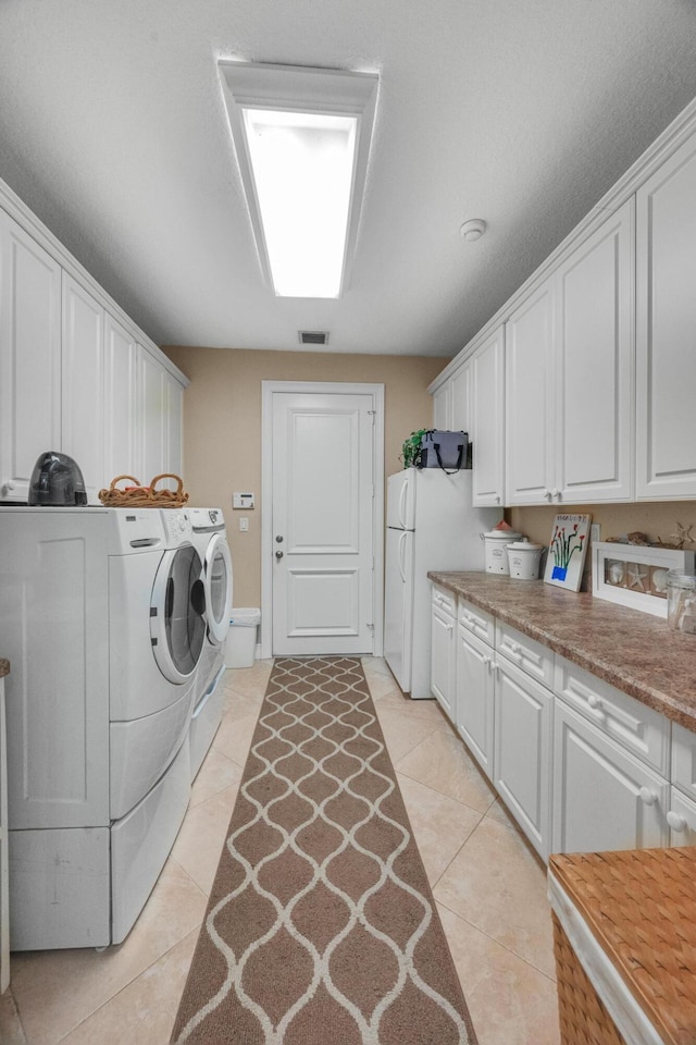 laundry room featuring light tile patterned floors, separate washer and dryer, and cabinets