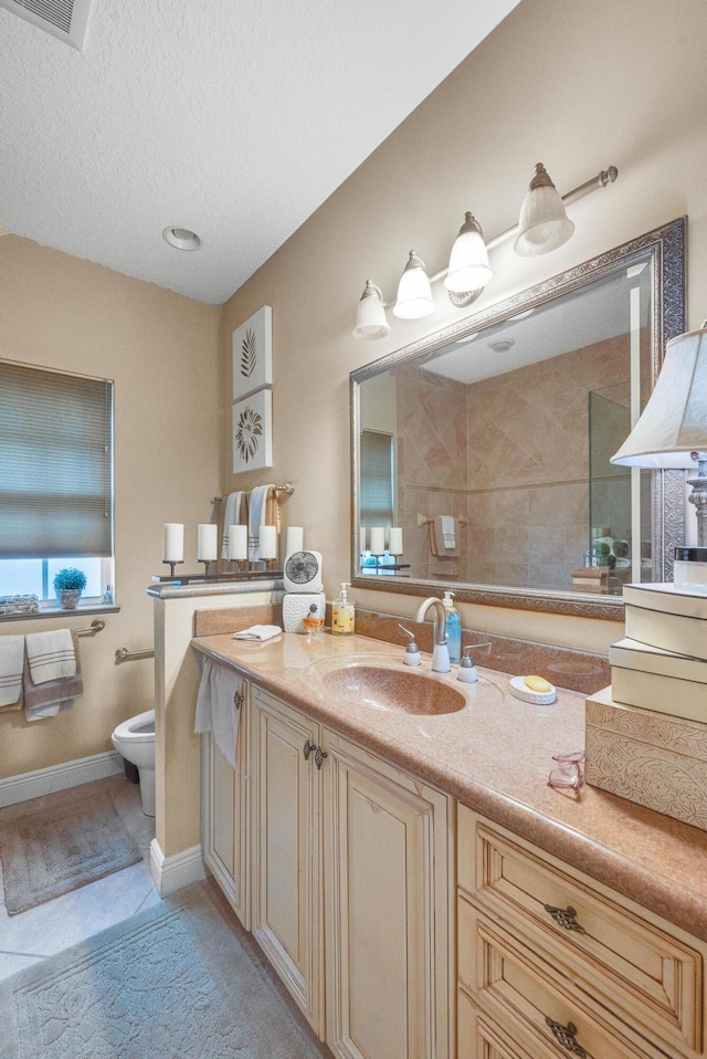 bathroom featuring vanity, toilet, tile patterned floors, and a textured ceiling