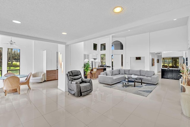 living room featuring a textured ceiling, light tile patterned flooring, and ceiling fan