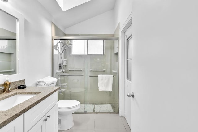 bathroom featuring a shower with shower door, vanity, lofted ceiling with skylight, toilet, and tile patterned floors