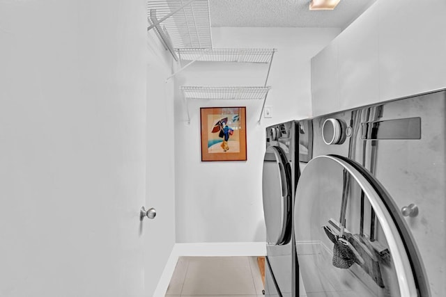 laundry area featuring light tile patterned floors, a textured ceiling, and independent washer and dryer