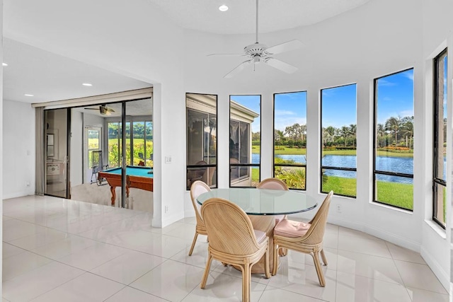 dining area with light tile patterned floors, a water view, ceiling fan, and billiards