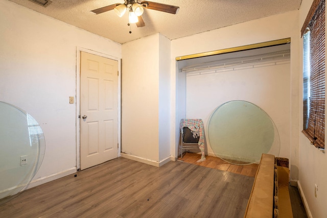 unfurnished bedroom with ceiling fan, a textured ceiling, a closet, and hardwood / wood-style floors