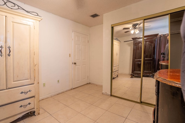 interior space featuring a closet, a textured ceiling, and light tile patterned flooring