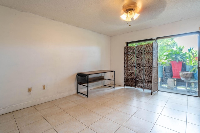 tiled empty room with ceiling fan and a textured ceiling