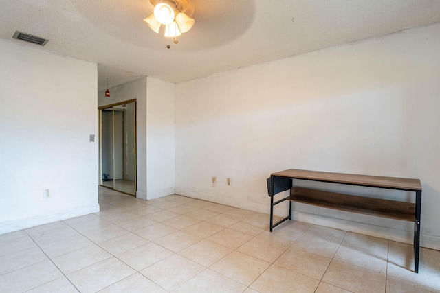 spare room with ceiling fan, light tile patterned floors, and a textured ceiling