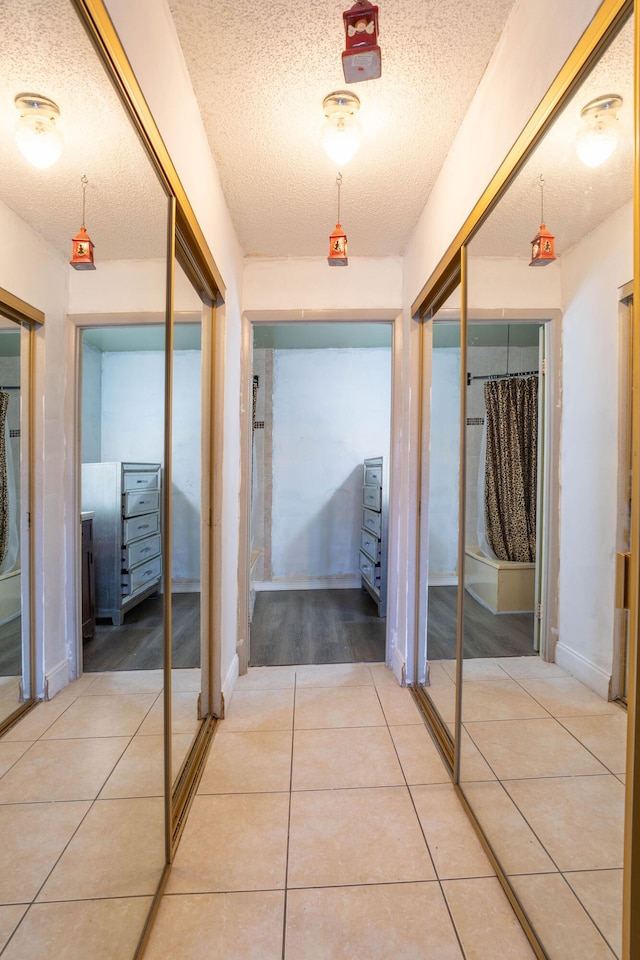 corridor featuring a textured ceiling and light tile patterned flooring