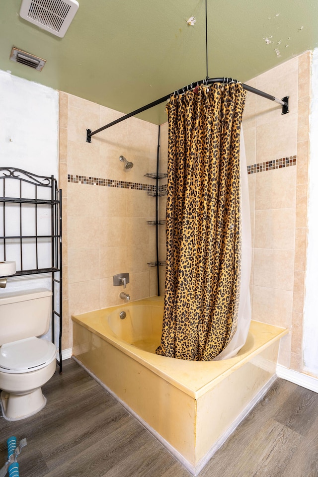 bathroom with shower / bath combo with shower curtain, hardwood / wood-style floors, and toilet