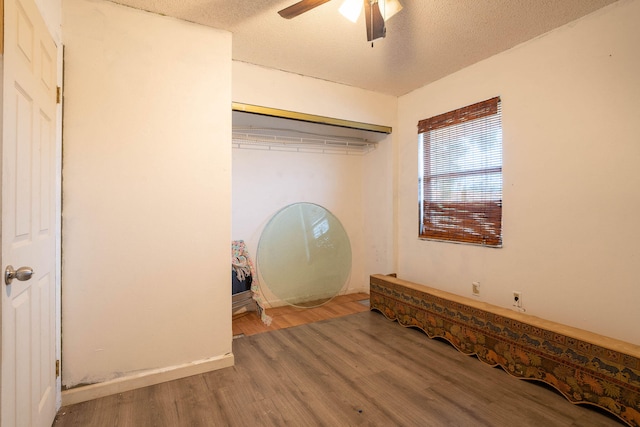 unfurnished bedroom featuring a closet, ceiling fan, hardwood / wood-style flooring, and a textured ceiling