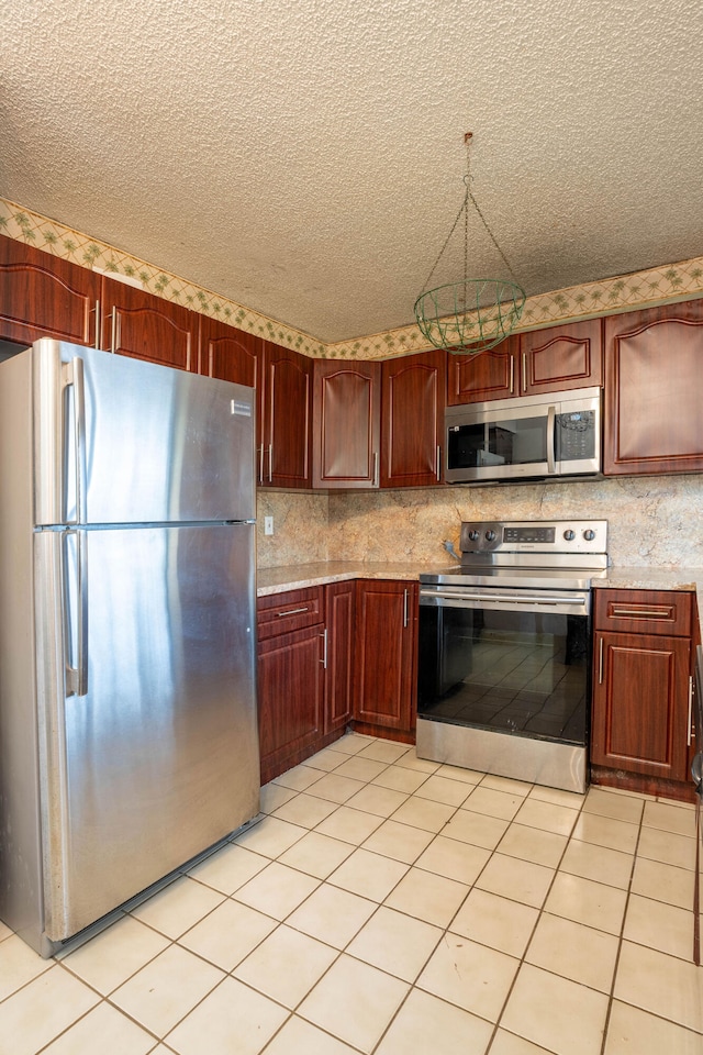 kitchen featuring a textured ceiling, appliances with stainless steel finishes, and light tile patterned flooring