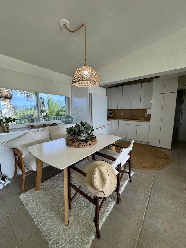 tiled dining space with vaulted ceiling and sink