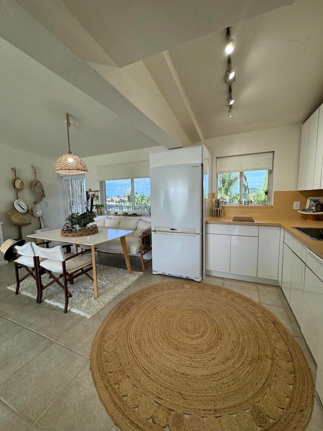 kitchen featuring track lighting, pendant lighting, white fridge, light tile patterned floors, and white cabinets