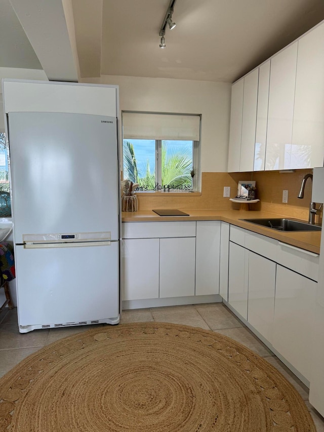 kitchen featuring white refrigerator, white cabinetry, and light tile patterned flooring