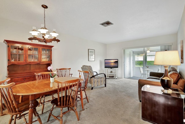 carpeted dining area with a notable chandelier and a textured ceiling