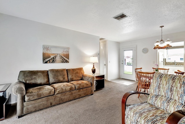 living room featuring a textured ceiling, light colored carpet, and a notable chandelier