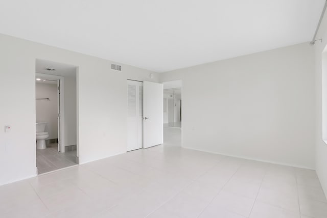 unfurnished bedroom with light tile patterned floors, ensuite bath, visible vents, and a closet