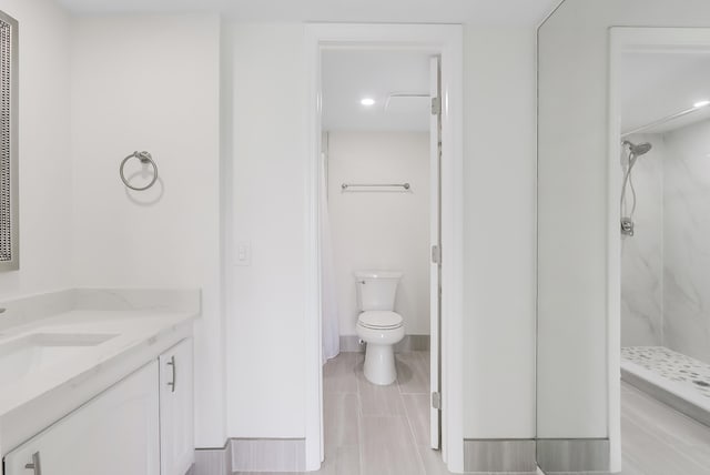 bathroom featuring toilet, a marble finish shower, and vanity