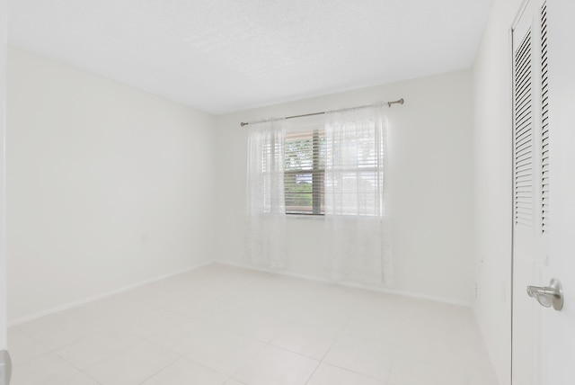 empty room with a textured ceiling and baseboards