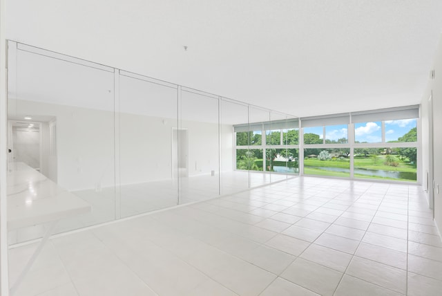 tiled empty room with a water view and expansive windows