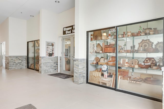 interior space featuring a wainscoted wall, a towering ceiling, and tile walls