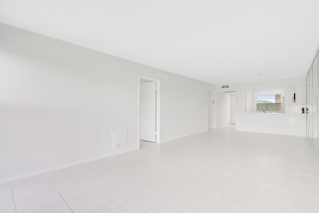 empty room featuring light tile patterned floors, baseboards, and visible vents