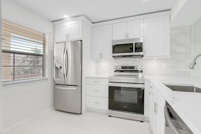 kitchen featuring a sink, appliances with stainless steel finishes, white cabinets, and backsplash