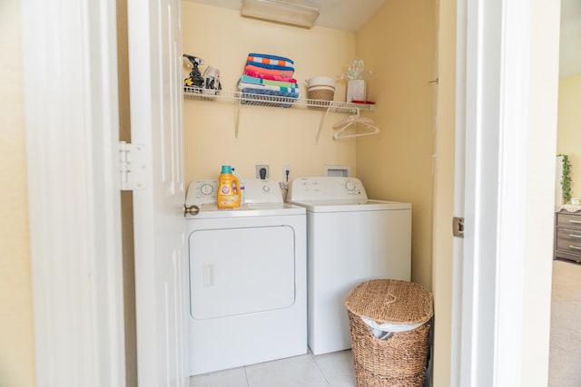 clothes washing area featuring light tile patterned flooring and washer and dryer