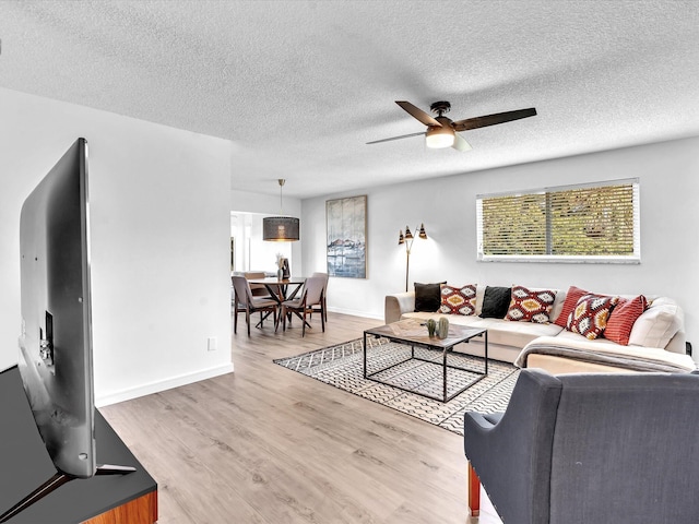 living room with ceiling fan, hardwood / wood-style floors, and a textured ceiling