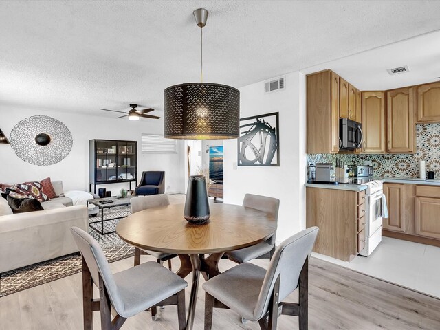 dining room featuring a textured ceiling, light hardwood / wood-style floors, and ceiling fan