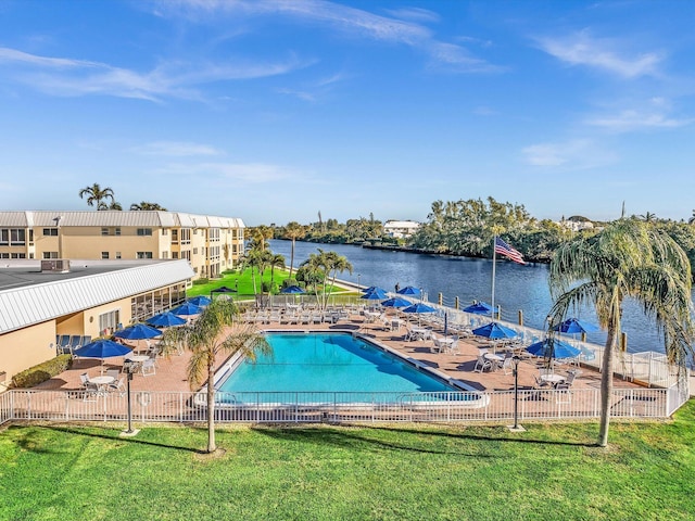 view of swimming pool with a lawn, a water view, and a patio