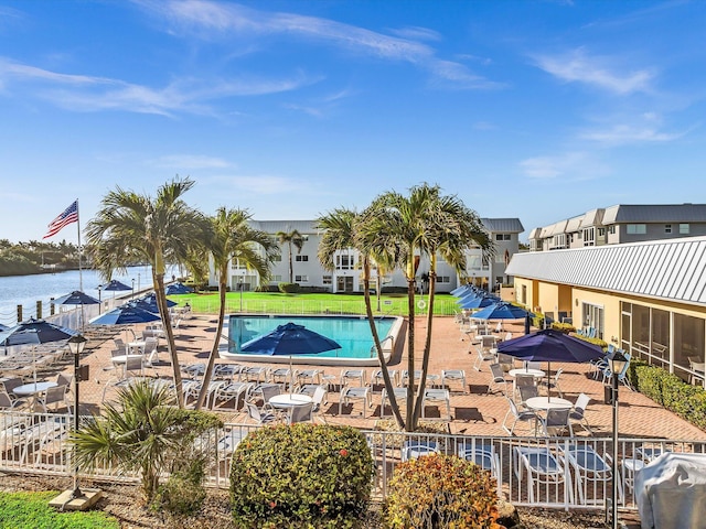 view of swimming pool featuring a grill, a water view, and a patio